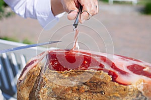 Spanish Iberian ham or Pata Negra mounted on a wooden stand with a butcher cutting slices of it