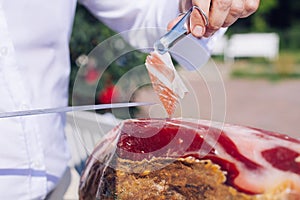 Spanish Iberian ham or Pata Negra mounted on a wooden stand with a butcher cutting slices of it