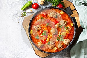 Hot stew tomato soup with meatballs and vegetables. Top view on a flat lay. Free space for