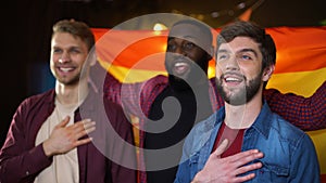 Spanish multiethnic male football fans singing national anthem and waving flag