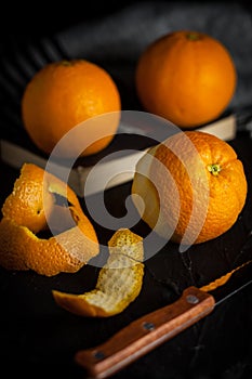 spanish oranges freshly on book and peels oranges before eating on black background,angle view