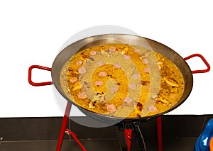 Spanish paella of meat, chicken and vegetables in a paella pan on a butane gas stove. copy space