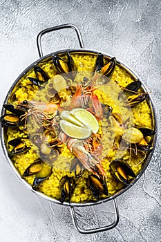 The Spanish paella with seafood prawns, shrimps, mussels in a paellera. White background. Top view. Copy space photo