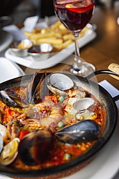 Spanish paella in a serving pan on a table in a cafe, close-up