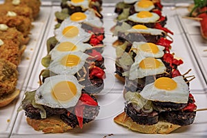 Spanish pintxos of morcilla blood sausage with egg and piquillo peppers in a Basque bar, San Sebastian, Spain