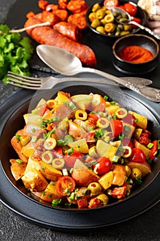 spanish potato salad with chorizo in black bowl