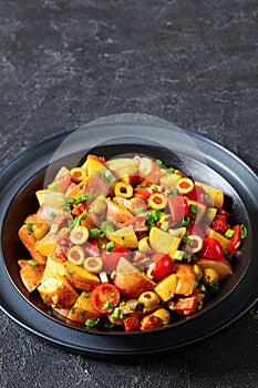 spanish potato salad with chorizo in black bowl