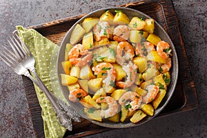 Spanish Potatoes roasted with Garlic Shrimp close-up in a plate. Horizontal top view