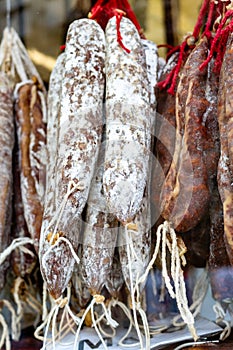 Spanish salami, fuet and salchichÃÂ³n sausages hang on a shelf against a black background photo