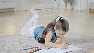 Spanish spaniard caucasian little small school girl daughter child pupil kid lying on floor draws picture drawing on