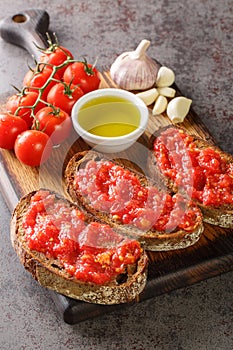 Spanish style toast with tomato Pan con tomate closeup on the wooden board. Vertical photo