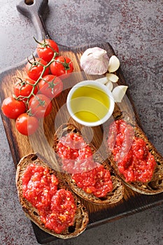 Spanish style toast with tomato Pan con tomate closeup on the wooden board. Vertical top view