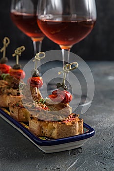 Spanish tapa pinxtos with tuna, peper, onion and oregano. Wine on background
