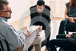 Spanish teenager listening to counselor during meeting of support group