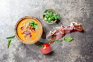 Spanish tomato soup Salmorejo served in olive wooden bowl with ham jamon serrano on stone background. Top view