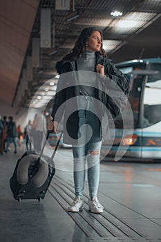 Spanish woman in black coat at a bus station