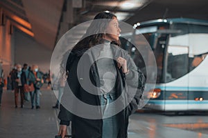 Spanish woman in black coat at a bus station