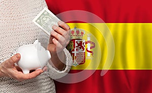 Spanish woman with money bank on the background of Spain flag. Dotations, pension fund, poverty, wealth, retirement concept