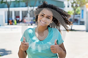 Spanish young woman with curly black hair showing boths thumbs up