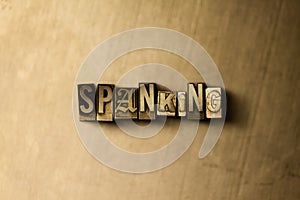 SPANKING - close-up of grungy vintage typeset word on metal backdrop