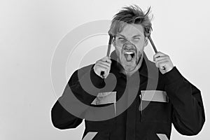 Spanner instruments for tightening details. Man with screaming face holds wrench tools near face