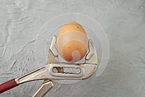 A Spanner wrench Holding An Egg on gray cement background