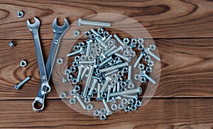 Spanners and nuts with bolts on a wooden surface