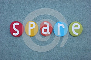 Spare, english word composed with multi colored stone letters over green sand