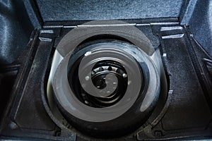 Spare rubber tire in the trunk of car