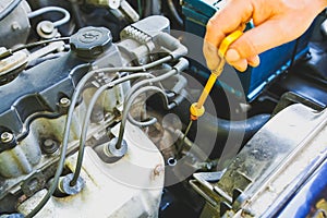 Spark plug in old car engine. Man checking oil level in the tank. Inner details of machine. Repairing of vehicle