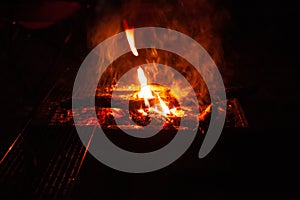 Sparking bonfire with tourist people sit around bright bonfire near camping tent in forest night background