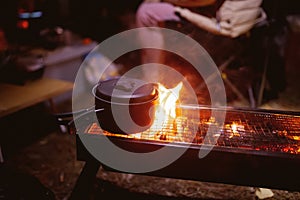 Sparking bonfire with tourist people sit around bright bonfire near camping tent in forest night background