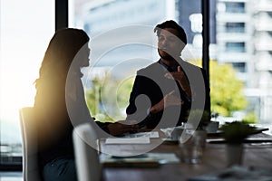 Sparking new ideas in the boardroom. Shot of two silhouetted businesspeople having a meeting in the boardroom.