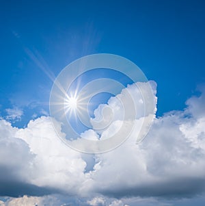 Sparkle sun above dense cumulus clouds on the blue sky background