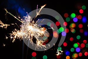 Sparkler on festive bokeh background. Festive greeting card for new year and christmas 2021, colorful lights in the background