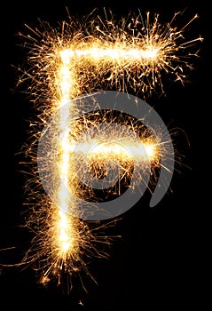 Sparkler firework light alphabet F on black