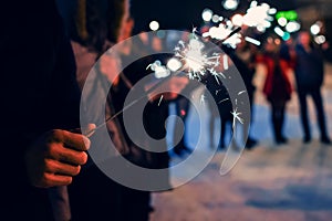 Sparkler in hands of people on holiday with sparks