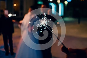 Sparkler with sparks in the hand of man on holiday on blurry background