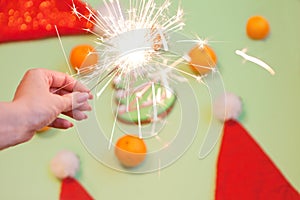 sparkler in woman hand near mandarines. christmas bengal light for celebrating on green background