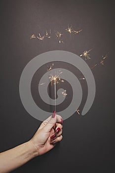 Sparkler in woman hand with red nail polish