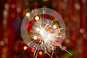 Sparklers near the Christmas tree with a red background