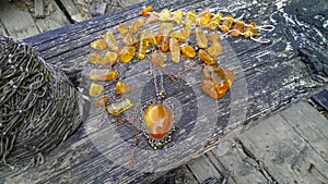 Sparkling Baltic amber pendant and necklace on the dilapidated wooden bench in the boat.