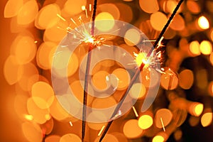 Sparkling bengal fire in the hands on shining bokeh background.Bengal lights on garlands.Holiday lights. Christmas