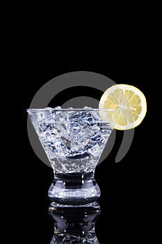 Sparkling beverage in a martini glass with lemon slice on a bl