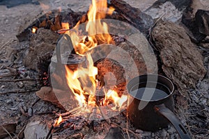 Sparkling bonfire with tea kettle and coffee pot in summer night background.