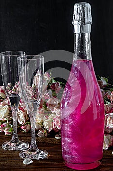 Sparkling brilliant raspberry drink. Champagne in two glasses stands on a wooden table with ice. For flowers and a garland