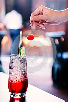 Sparkling cherry lime cocktail with ice cubes in clear glass on table