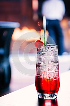 Sparkling cherry lime cocktail with ice cubes in clear glass on table