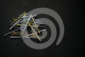 Sparkling metal silver gold and black hairpins on a black background. A pile of hairpins for evening and festive hairstyles. Even