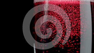Sparkling of red sparkling wine. Red wine being poured into a glass of black background. Slow motion